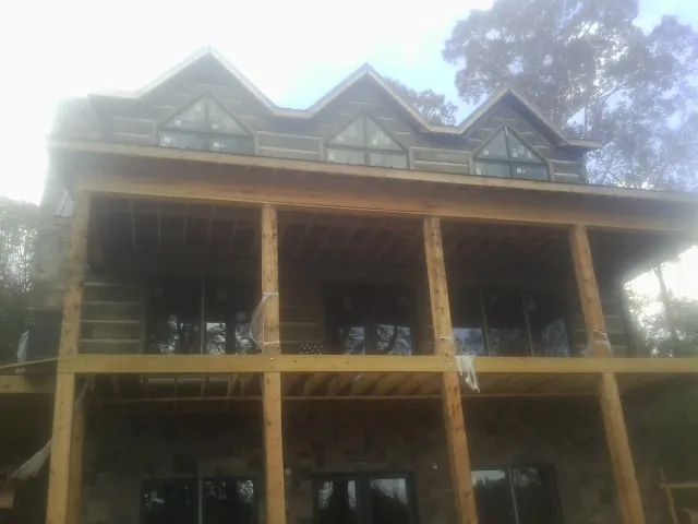 Dormers and porch framing on a large log home under construction — Roof Coating work by our crew in Salina