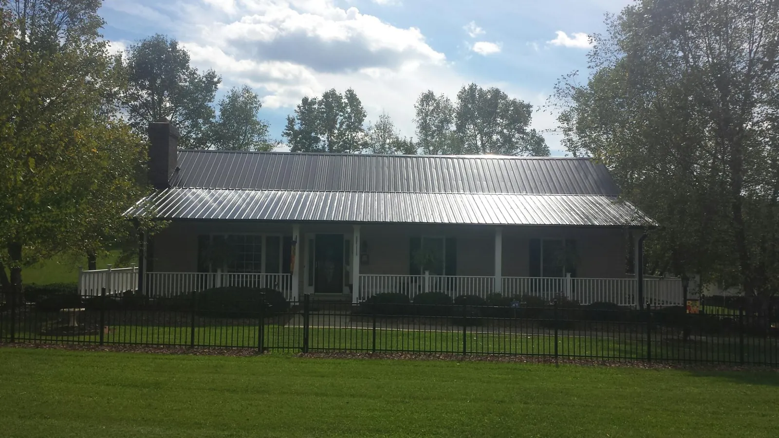 Gray metal roof on a brick ranch with a full width front porch — Gutter Guard Installation work by our crew in Salina