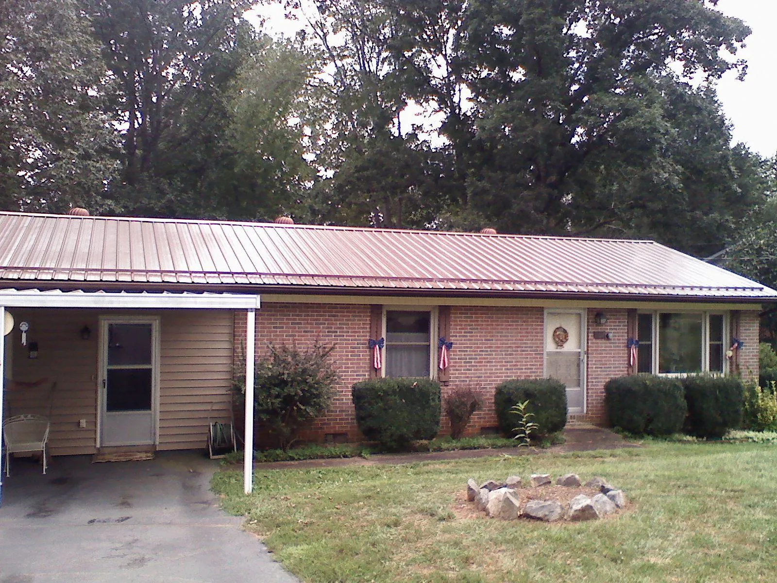 Bronze metal roof and carport on a brick ranch home — Roof Repair work by our crew in Salina