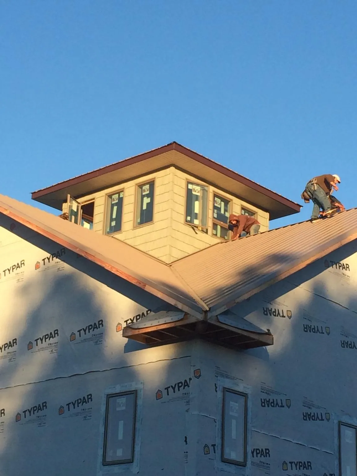 Roofers working around a rooftop cupola on a new metal roof at sunset — Roof Waterproofing in Salina by Roofing Brothers